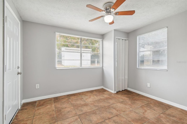 unfurnished bedroom featuring light tile patterned floors, a textured ceiling, and ceiling fan