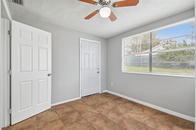 unfurnished bedroom featuring tile patterned floors, ceiling fan, a closet, and a textured ceiling