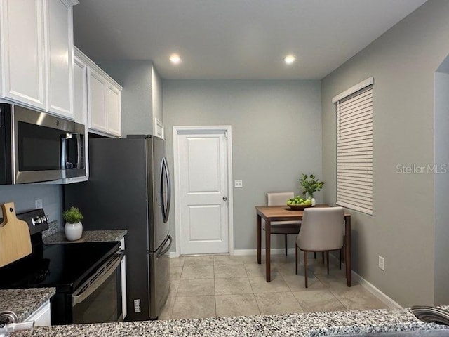 kitchen featuring light tile patterned flooring, white cabinetry, black range with electric stovetop, and stone countertops