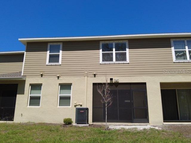 rear view of house featuring cooling unit and a lawn