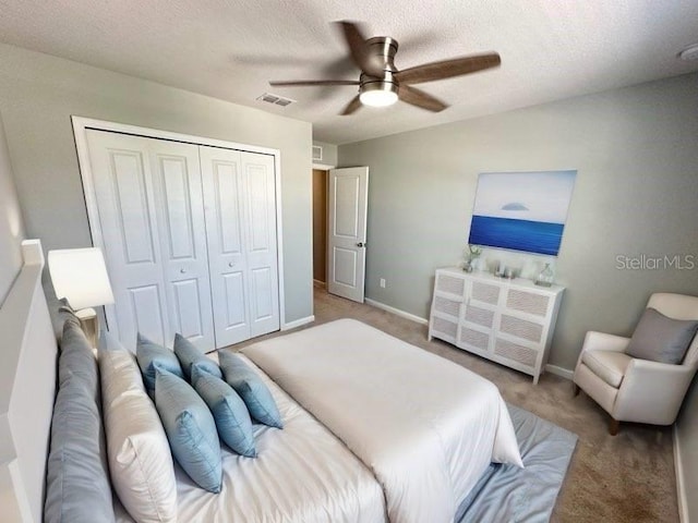 bedroom with ceiling fan, light colored carpet, a textured ceiling, and a closet