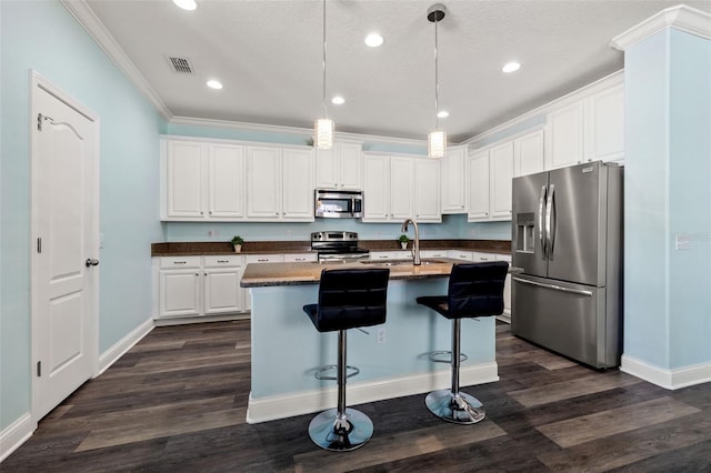 kitchen featuring appliances with stainless steel finishes, pendant lighting, sink, white cabinets, and a center island with sink