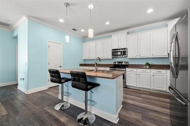 kitchen with pendant lighting, a breakfast bar, appliances with stainless steel finishes, white cabinetry, and a center island with sink