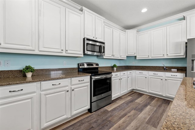 kitchen featuring stainless steel appliances, white cabinets, dark hardwood / wood-style flooring, and dark stone counters