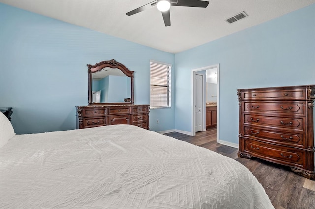 bedroom with ensuite bath, dark wood-type flooring, and ceiling fan