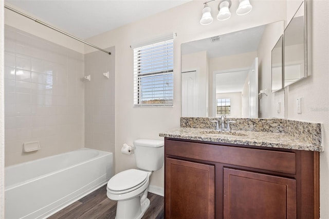 full bathroom featuring hardwood / wood-style flooring, tiled shower / bath, vanity, and toilet