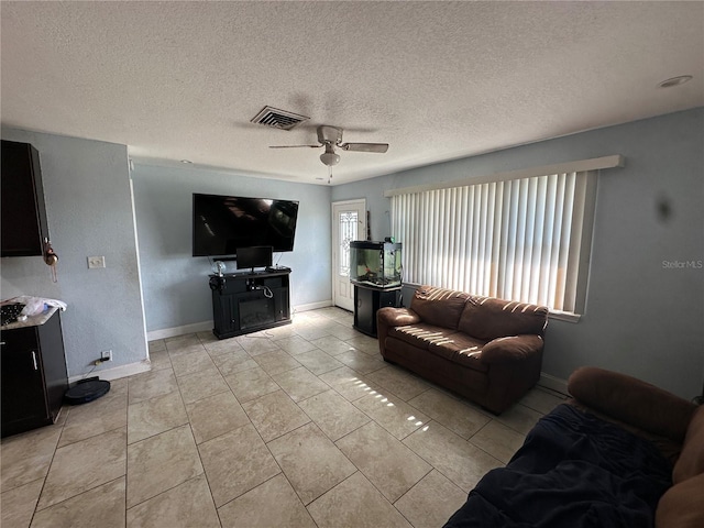 tiled living room featuring a textured ceiling, ceiling fan, and a healthy amount of sunlight