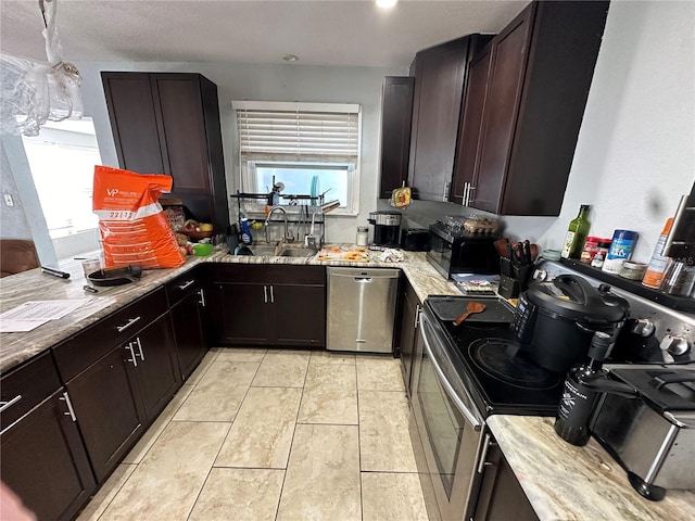 kitchen featuring sink, light tile patterned floors, dark brown cabinets, light stone counters, and stainless steel appliances