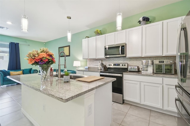 kitchen featuring backsplash, a center island with sink, white cabinets, and appliances with stainless steel finishes