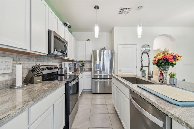 kitchen with appliances with stainless steel finishes, backsplash, sink, white cabinetry, and light tile patterned flooring