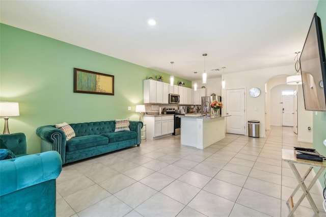 kitchen featuring white cabinetry, stainless steel appliances, backsplash, pendant lighting, and a kitchen island with sink