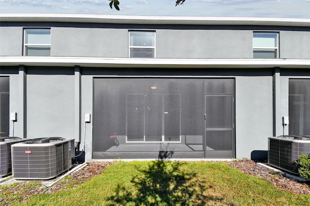 back of house featuring central AC unit, a sunroom, and a yard