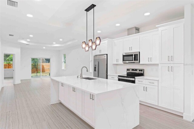 kitchen with white cabinets, sink, hanging light fixtures, appliances with stainless steel finishes, and a large island