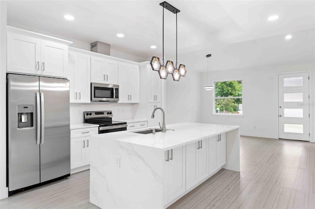 kitchen with pendant lighting, a center island with sink, white cabinets, and stainless steel appliances