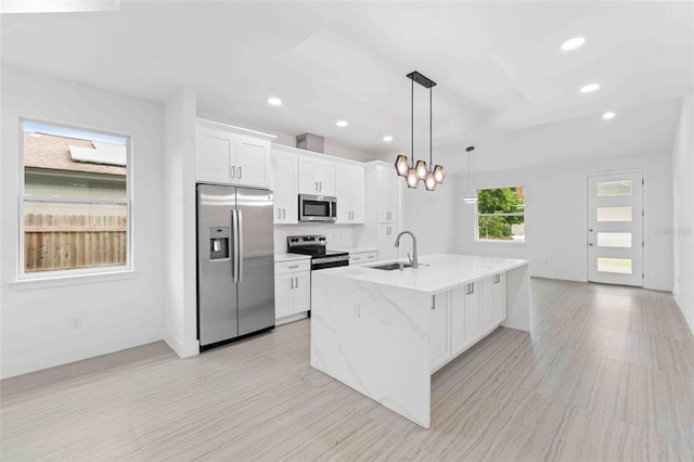 kitchen with white cabinets, a center island with sink, hanging light fixtures, sink, and appliances with stainless steel finishes