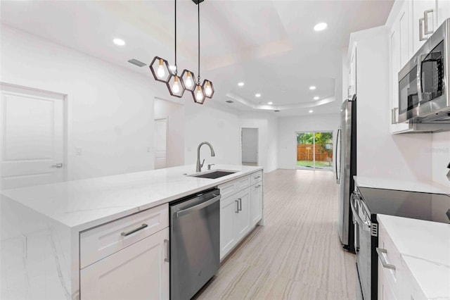 kitchen with appliances with stainless steel finishes, white cabinetry, hanging light fixtures, and light stone counters