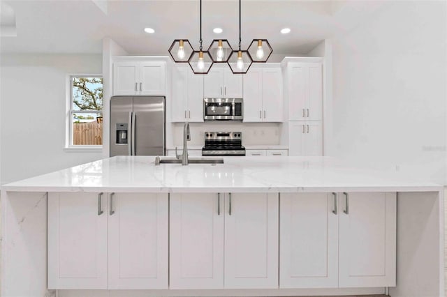 kitchen with light stone countertops, stainless steel appliances, sink, pendant lighting, and white cabinets