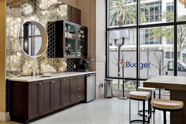 bar with decorative backsplash, dark brown cabinets, and sink