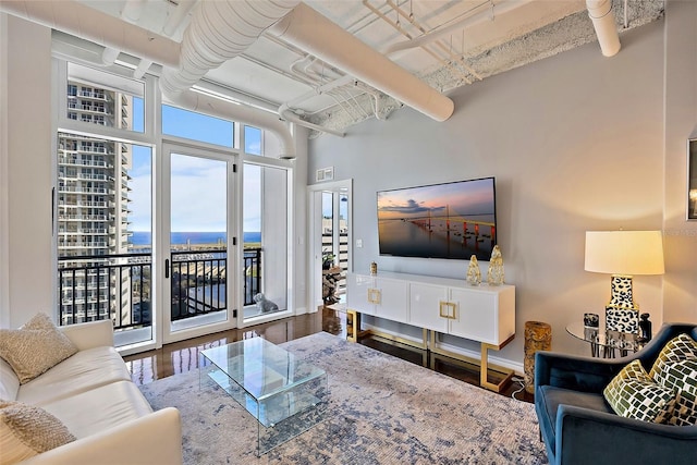 living room with hardwood / wood-style flooring, expansive windows, and a towering ceiling