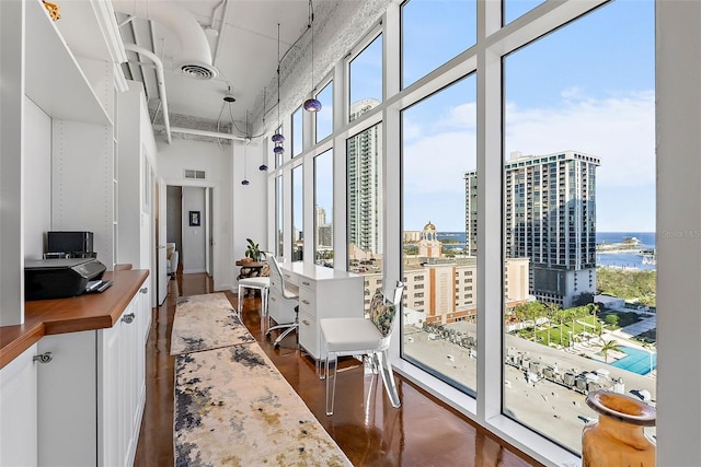 interior space with expansive windows, plenty of natural light, a towering ceiling, and concrete floors