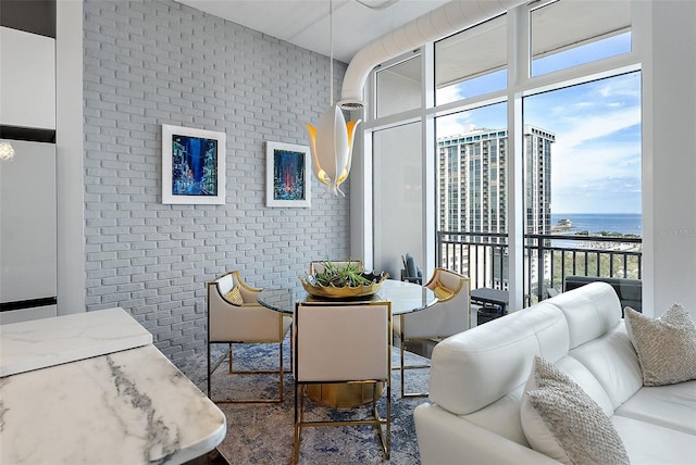 dining area featuring floor to ceiling windows, a water view, and brick wall