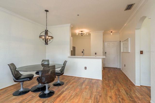 dining area with a chandelier, wood-type flooring, crown molding, and sink