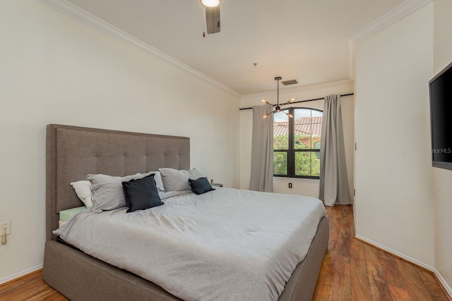 bedroom featuring crown molding, ceiling fan with notable chandelier, and hardwood / wood-style flooring