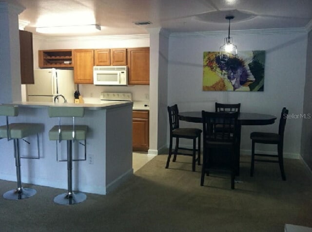 kitchen featuring pendant lighting, a breakfast bar, white appliances, and ornamental molding