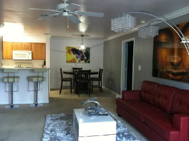 carpeted living room featuring crown molding and ceiling fan