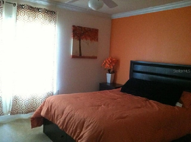 carpeted bedroom featuring ceiling fan and ornamental molding