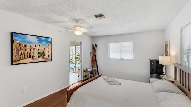 bedroom featuring ceiling fan, hardwood / wood-style floors, and a textured ceiling