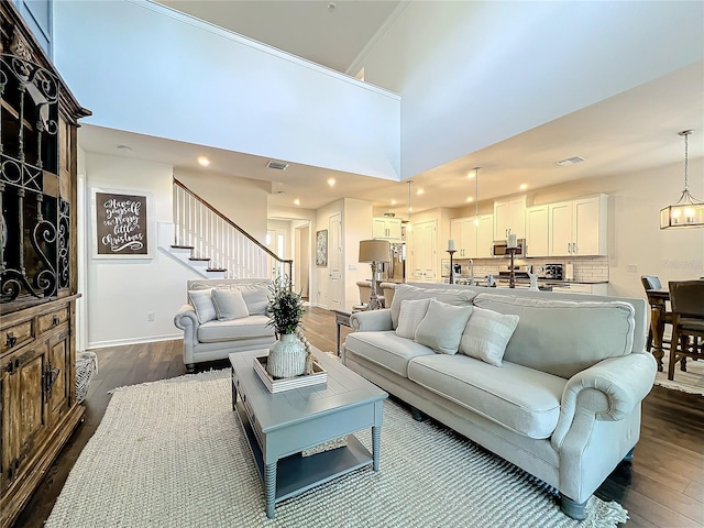 living room featuring ornamental molding, dark hardwood / wood-style floors, a high ceiling, and a notable chandelier