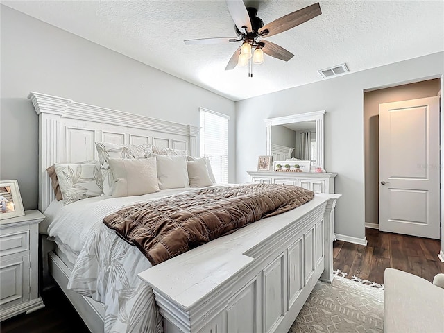 bedroom with a textured ceiling, dark wood-type flooring, and ceiling fan