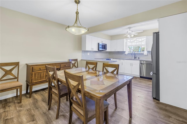 dining space with hardwood / wood-style flooring, ceiling fan, and sink