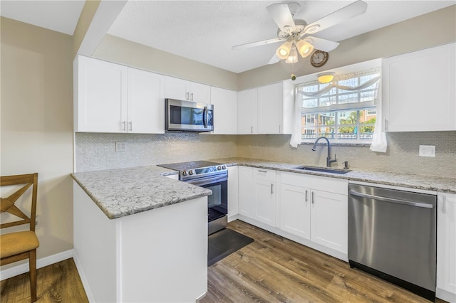 kitchen with decorative backsplash, appliances with stainless steel finishes, dark hardwood / wood-style flooring, sink, and white cabinetry