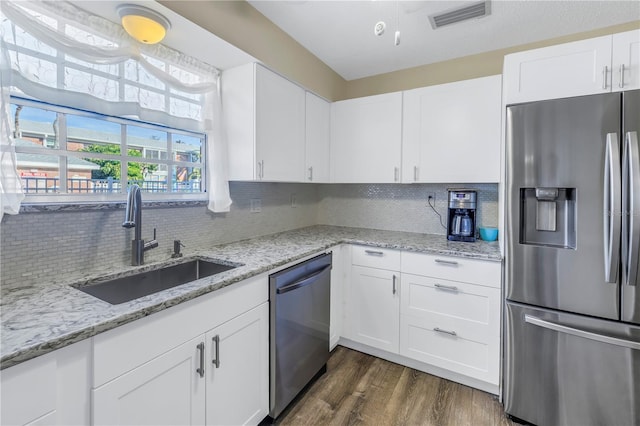 kitchen featuring white cabinetry, sink, light stone counters, dark hardwood / wood-style floors, and appliances with stainless steel finishes