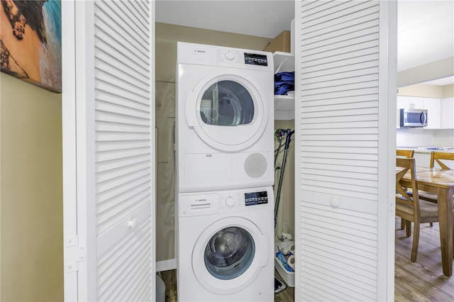 laundry area with hardwood / wood-style floors and stacked washer / drying machine