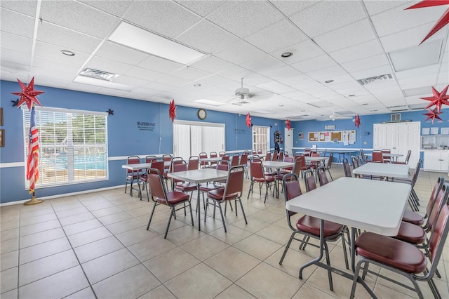 tiled dining space with a drop ceiling and ceiling fan