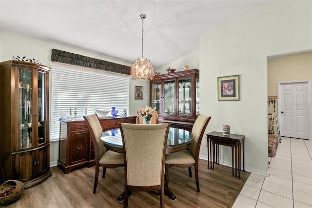 dining room with light hardwood / wood-style flooring and vaulted ceiling