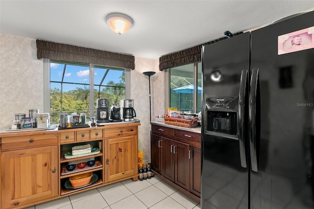 kitchen featuring black fridge, light tile patterned flooring, and a healthy amount of sunlight