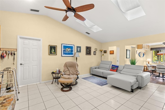 living room with vaulted ceiling with skylight, ceiling fan, and light tile patterned flooring