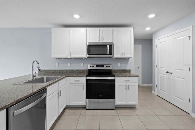 kitchen featuring sink, light tile patterned floors, a textured ceiling, white cabinetry, and stainless steel appliances