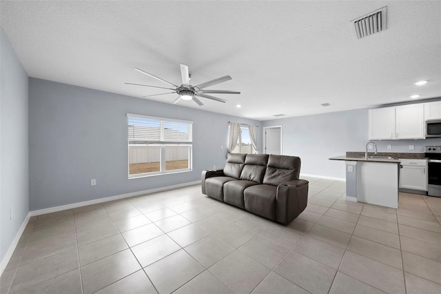 tiled living room featuring a textured ceiling, ceiling fan, and sink