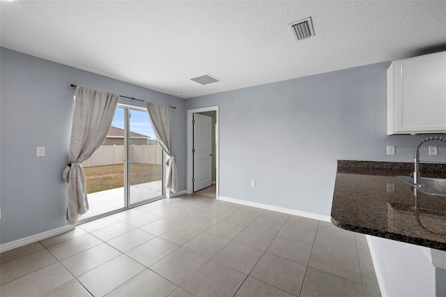 unfurnished dining area with a textured ceiling, light tile patterned flooring, and sink