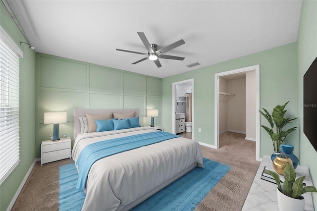 carpeted bedroom with a walk in closet, ceiling fan, and a closet