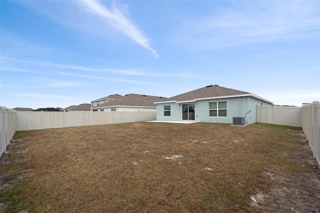 rear view of property with central AC unit and a lawn