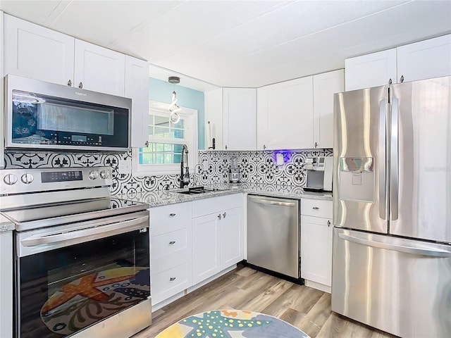 kitchen with white cabinets, sink, tasteful backsplash, light hardwood / wood-style floors, and stainless steel appliances