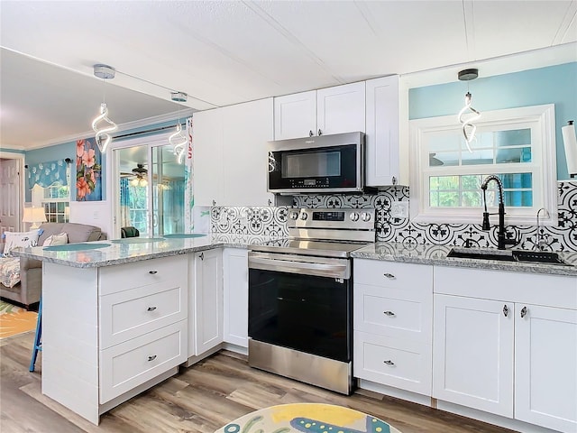 kitchen with sink, white cabinets, stainless steel appliances, and decorative light fixtures