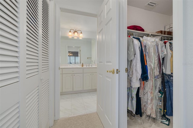 spacious closet with marble finish floor, visible vents, and a sink