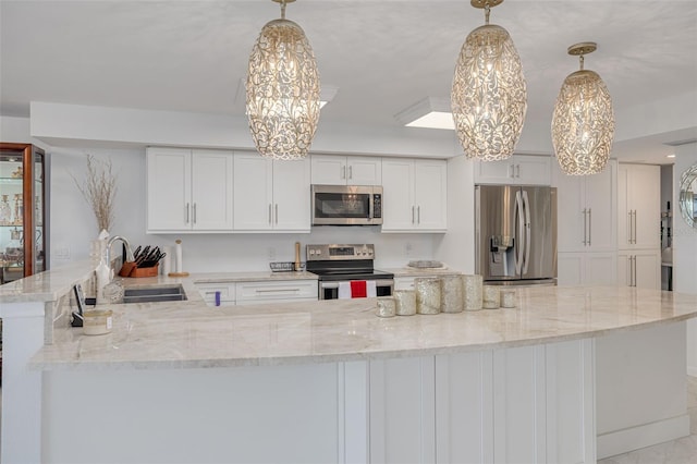 kitchen featuring white cabinets, light stone counters, appliances with stainless steel finishes, decorative light fixtures, and a sink